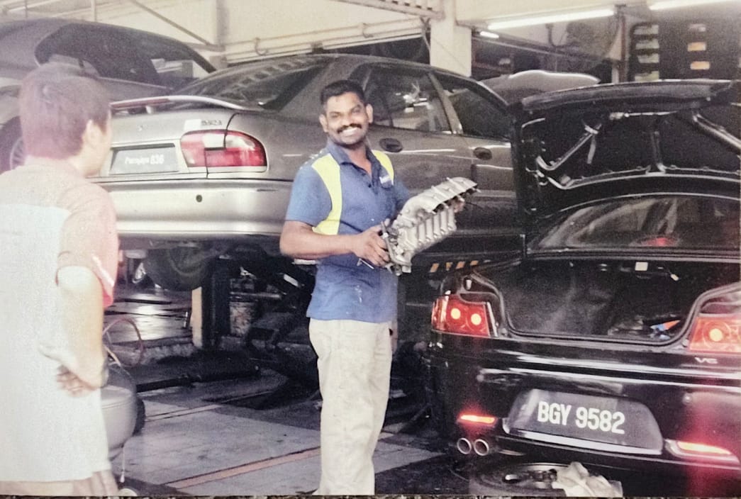 Kannan holding an engine part at the workshop